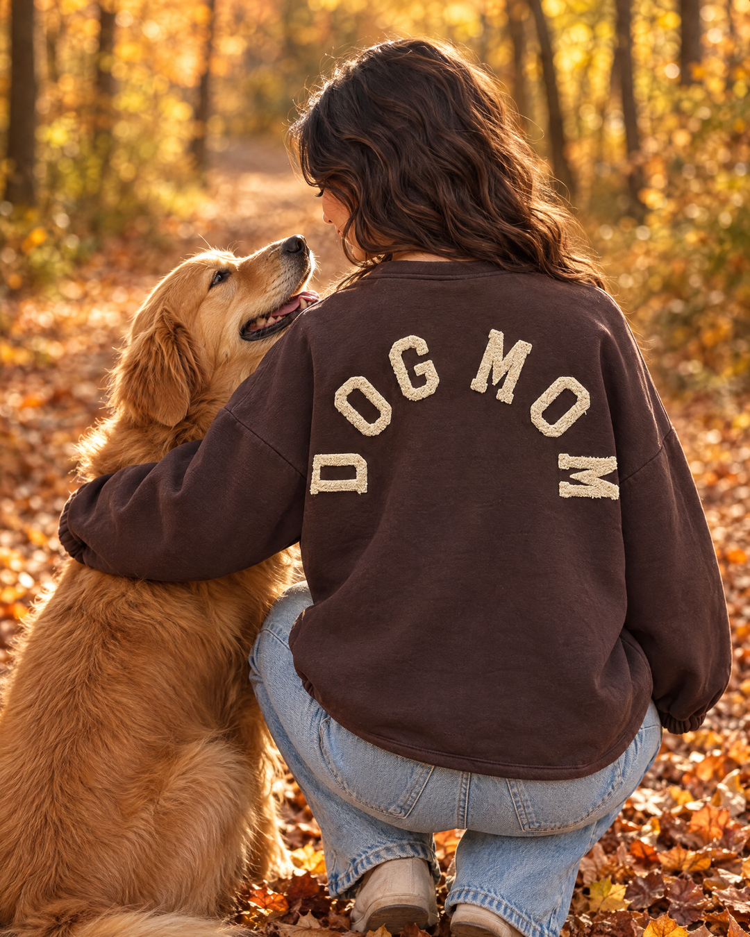 Frau im Dog Mom Sweatshirt in Schokobraun mit Golden Retriever im Herbstwald (KI-Bild)